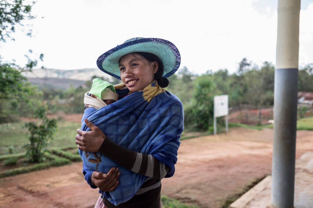 A young woman carrying a baby.